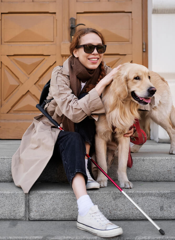 Women with visual impairments, seated on a step with her service dog.