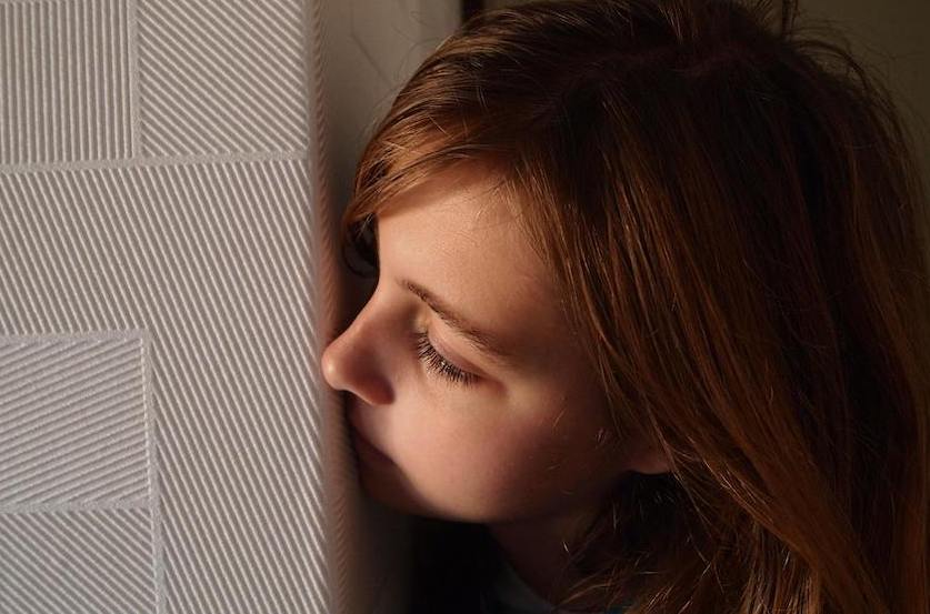 A little girl steals a glimpse around the corner of a wall