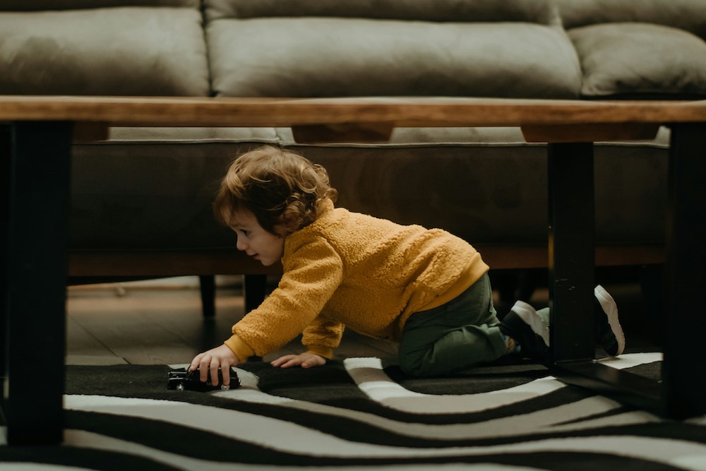 ADHD Little boy on his knees chases his car around the floor