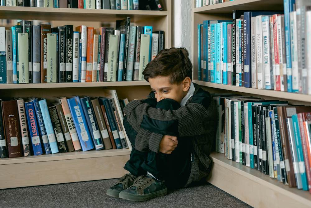 Child hiding in the corner of a library