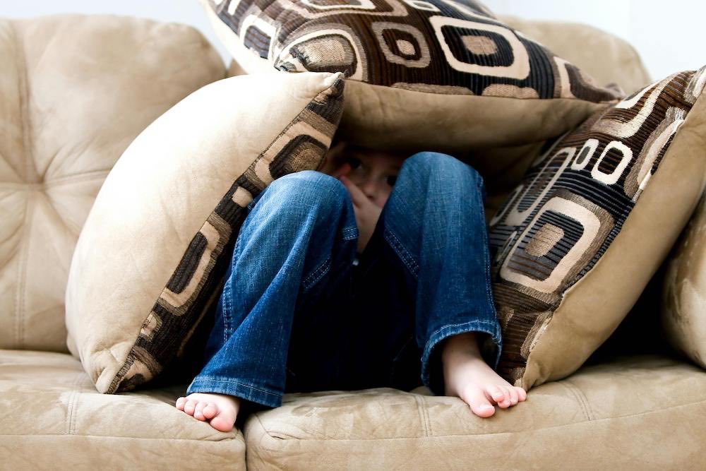 Child with Aspergers hides under pillows